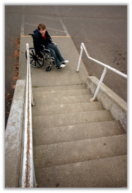 picture of a boy  in a wheelchair whoi cannot get up the steps becasue they are not wheelchair accessible