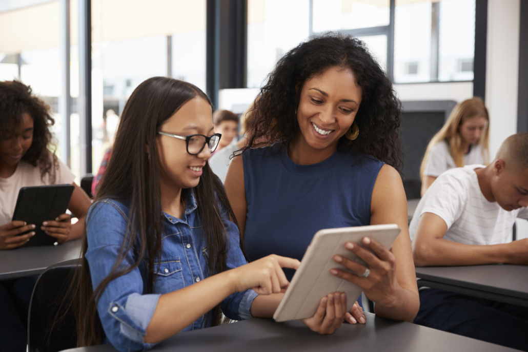 Teacher helping teenage schoolgirl with tablet computer
